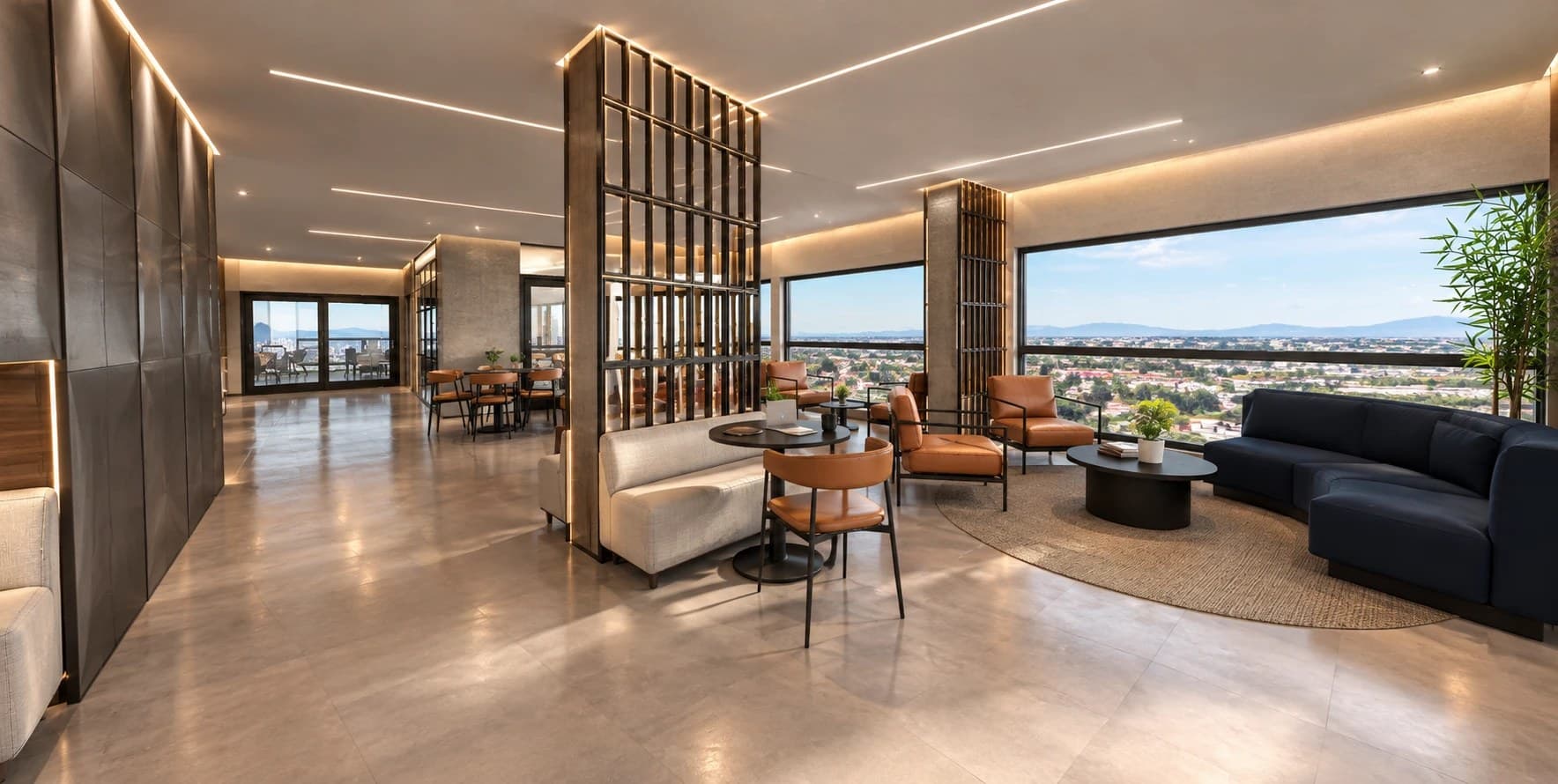 Lounge com sofá curvo, poltronas e mesas de trabalho junto às janelas